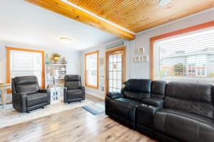 a living room with a leather couch and two chairs at Ocean Shells Cottage in Rockaway Beach
