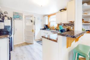 a kitchen with white cabinets and a green stool at Ocean Shells Cottage in Rockaway Beach +30 photos