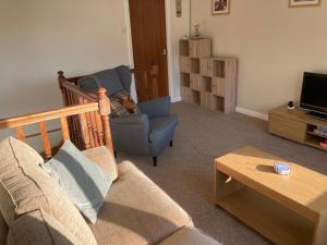 a living room with a couch and a chair and a tv at Edgemont Annexe Oban in Oban