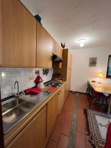 uma cozinha com armários de madeira, um lavatório e uma mesa em casa nel bosco cir vda 0192 em Courmayeur
