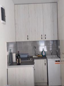 a kitchen with white cabinets and a bottle of wine at Apartment Iva in Bijela