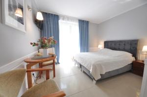 a bedroom with a bed and a table with a chair at Ambasador Villa, 150m do plaży, przy Centrum in Mielno