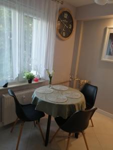 uma mesa de jantar com cadeiras e um relógio na parede em Apartament Euro 1 Bytom em Bytom