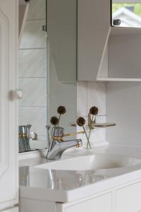 a white bathroom sink with flowers in a mirror at Exclusive house with private boathouse in Nösund