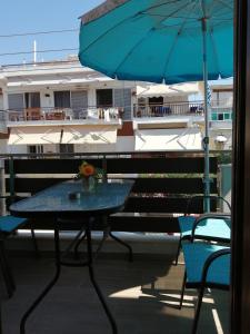 una mesa con sillas y una sombrilla en el balcón en Perla studios en Paralia Dionysiou