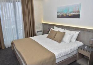 una camera d'albergo con letto con lenzuola e cuscini bianchi di Apartman Milinović Zlatibor - Hotel Alibi a Zlatibor