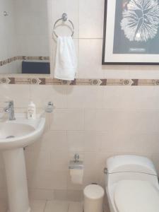 y baño con aseo blanco y lavamanos. en Cómodo y Equipado Apt Cerca del Malecón, en Santo Domingo