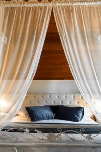 Cama con dosel, cortinas blancas y almohadas azules en Hotel Kehl Haus, en Gramado