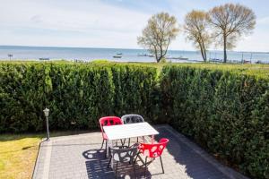 a table and two chairs sitting next to a hedge at Domki wakacyjne Koral in Swarzewo