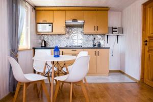 a kitchen with a table and white chairs in a room at Domki wakacyjne Koral in Swarzewo