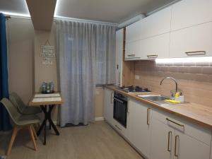 een keuken met een tafel, een wastafel en een aanrecht bij Pandora Central Apartment in Cluj-Napoca