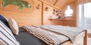 a bed in a room with a wooden wall at Treehouse U lesa in Osečná