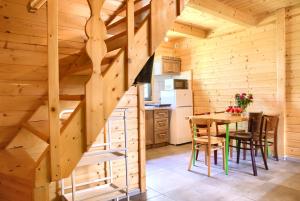 a kitchen and dining room with a wooden staircase in a log cabin at Kolorowe Domki Rewal in Rewal