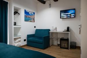 a bedroom with a blue chair and a desk at Sofi' Center Rooms in Sciacca
