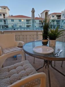 een tafel en stoelen op een patio met uitzicht op een gebouw bij Cozy ground floor appartment with communal pool in Paralimni