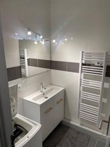 een witte badkamer met een wastafel en een spiegel bij le Barcarès appartement bord de mer in Le Barcarès