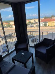 een woonkamer met 2 stoelen en een tafel en een balkon bij le Barcarès appartement bord de mer in Le Barcarès