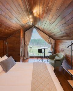una camera da letto con un letto grande con soffitto in legno di Nordic Cabanas a Cambará