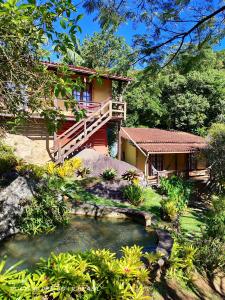 a house with a pond in front of it at Pousada luar da serra in Lumiar