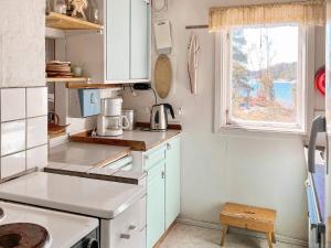 una pequeña cocina con armarios blancos y una ventana en Holiday home DALARÖ II en Dalarö