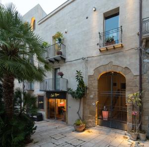 a building with a palm tree in front of it at Sofi' Center Rooms in Sciacca
