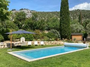 a swimming pool in a yard with an umbrella at Chante Coucou in Saint-Saturnin-lès-Apt