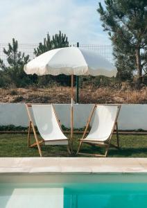 two chairs and an umbrella next to a swimming pool at Quinta Amarela - B&B in Nazaré