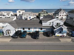 a group of cars parked in a parking lot in front of a house at Patras Grand Beach Motel in Old Orchard Beach