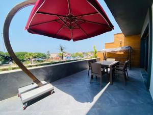 een patio met een rode parasol en een tafel en stoelen bij KUSADASI SOGUCAKTA 2+1 TERASLI DENIZE YAKIN LUKS DAIRE in Kuşadası