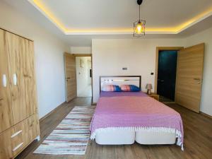 een slaapkamer met een groot bed en houten vloeren bij KUSADASI SOGUCAKTA 2+1 TERASLI DENIZE YAKIN LUKS DAIRE in Kuşadası