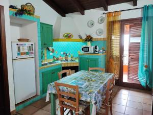 cocina con armarios verdes, mesa y nevera en Il Fenicottero 2 en Masainas