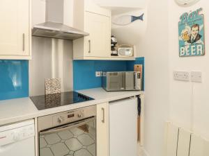 a small kitchen with white cabinets and a microwave at Lake Victoria Cottage in Dartmouth