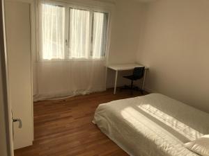 a bedroom with a bed and a desk and a window at GRENOBLE JOLI APPARTEMENT in Grenoble