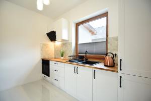 a kitchen with white cabinets and a window at Domki Lilia Sarbinowo in Sarbinowo