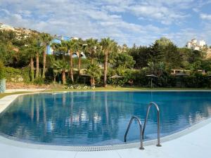 a large swimming pool with blue water and palm trees at Casa del Mar in Zahara de los Atunes