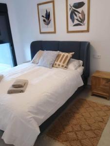 uma cama com lençóis brancos e almofadas num quarto em Gran Apartment-Iconic Sea View em Gran Alacant
