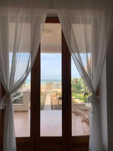een deur met gordijnen en een balkon met uitzicht bij Casa On The Beach in Alcamo