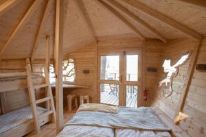 1 dormitorio en una cabaña de madera con cama y escalera en Treehouse U rybníka, en Osečná