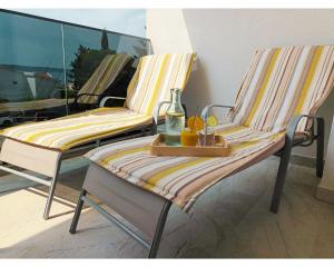 2 Stühle auf einem Balkon mit einem Getränk und einem Tablett in der Unterkunft Sun Side - Čiovo in Trogir
