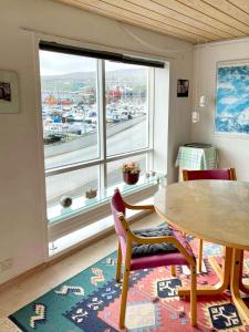 ein Esszimmer mit einem Tisch und einem großen Fenster in der Unterkunft Guesthouse at the boat harbour in Tórshavn