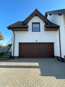 a white house with a brown garage door at Apartament letni Almar in Pogórze