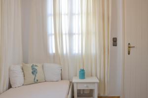 Cette chambre dispose d'une fenêtre avec un canapé et une table. dans l'établissement ANIMA family apartment, à Naxos Chora