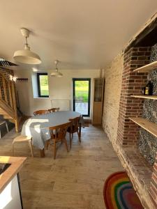 una sala da pranzo con tavolo e muro di mattoni di Gite confortable au milieu des prés - La ferme de Montigny a Neauphe-sur-Dives