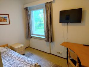 a bedroom with a bed and a television and a window at Hostel Vanha Koulu in Monola