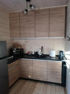 une cuisine avec des placards en bois et un comptoir noir dans l'établissement Nadmorska Sarbinowo, à Sarbinowo