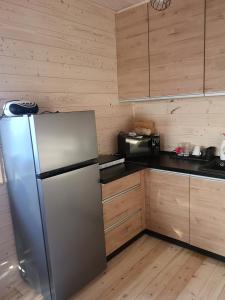 kuchnia z lodówką ze stali nierdzewnej i drewnianymi szafkami w obiekcie Nadmorska Sarbinowo w Sarbinowie
