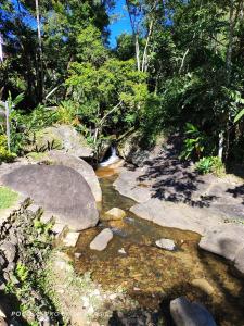 una corriente de agua con rocas y árboles en Pousada luar da serra, en Lumiar