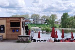 a man standing next to a building with tables and red umbrellas at L'Envol in Orléans