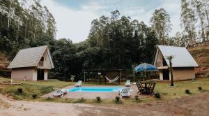a house with a pool and a swing at Recanto da Serra Chalé 02 in Mauá da Serra