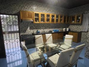 uma cozinha com uma mesa de vidro e cadeiras brancas em Tropical Paradise em São Tomé